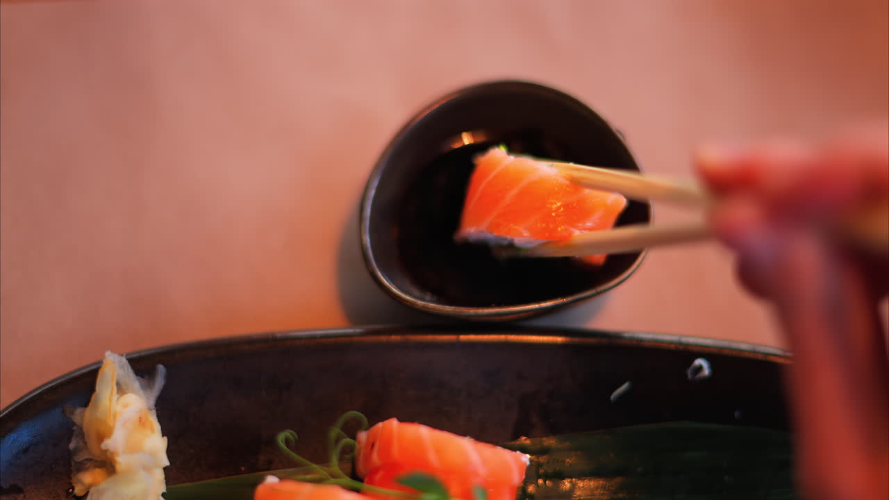 Close up of a woman dipping a Philadelphia sushi roll in soy sauce at a restaurant