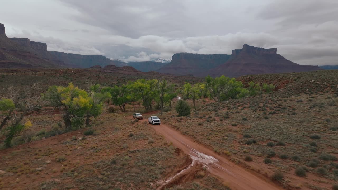 Car drives on dirt road through stunning desert landscape in Moab
