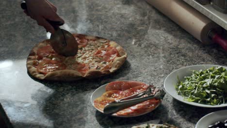 pizzaiolo cutting fresh hot pizza