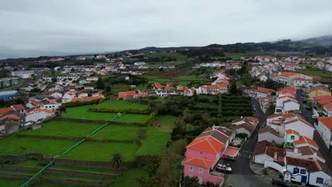 backwards aerial shot over green fields reveals obelisco in angra, terceira