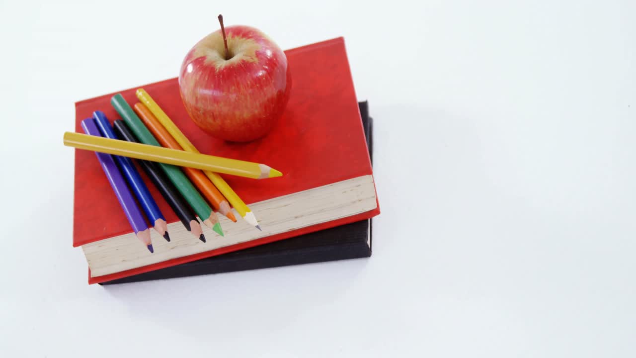 manzana y lápiz de color en la pila de libros