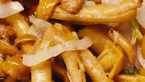 Close-up of fermented yellow honeydew mushrooms with onion on plate. Preservation of vegetables in glass jars. Fermentation preserved mushroom with spices rotating macro.