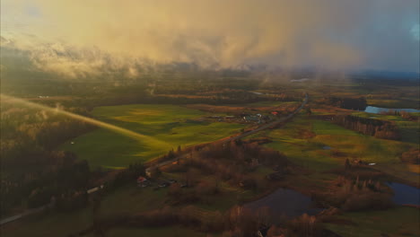 Aerial---Flight-near-clouds-over-lush-green-landscape-at-sunset