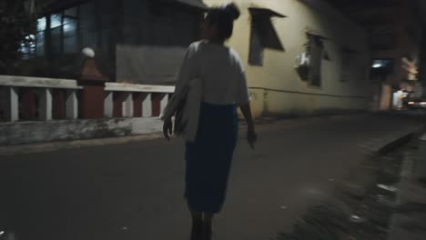 Under-the-glow-of-street-lights,-a-young-woman-walks-through-the-night-cityscape-holding-a-bunch-of-keys-in-her-hand,-ready-to-unlock-her-front-door