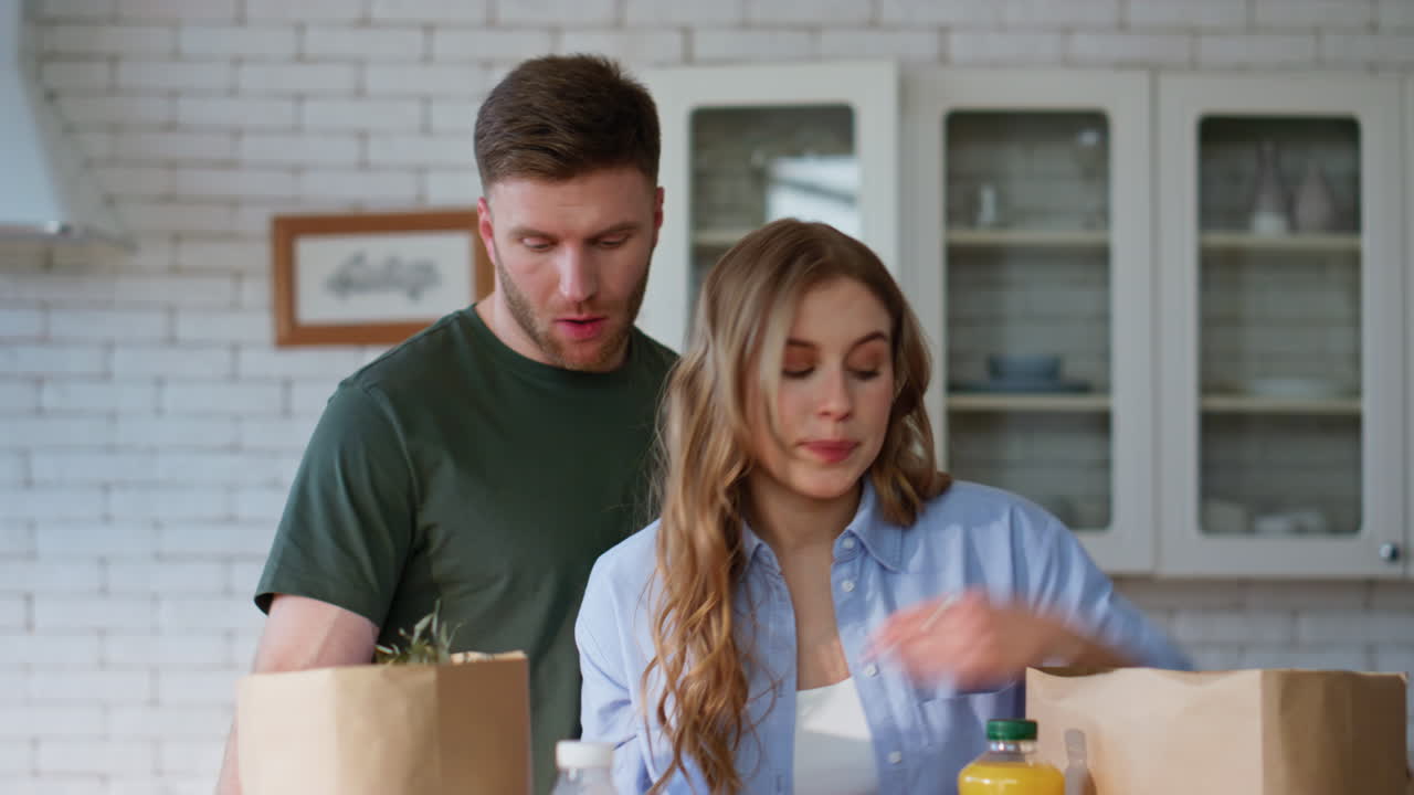 Closeup talking couple unpacking purchased food in bags. Spouses taking products
