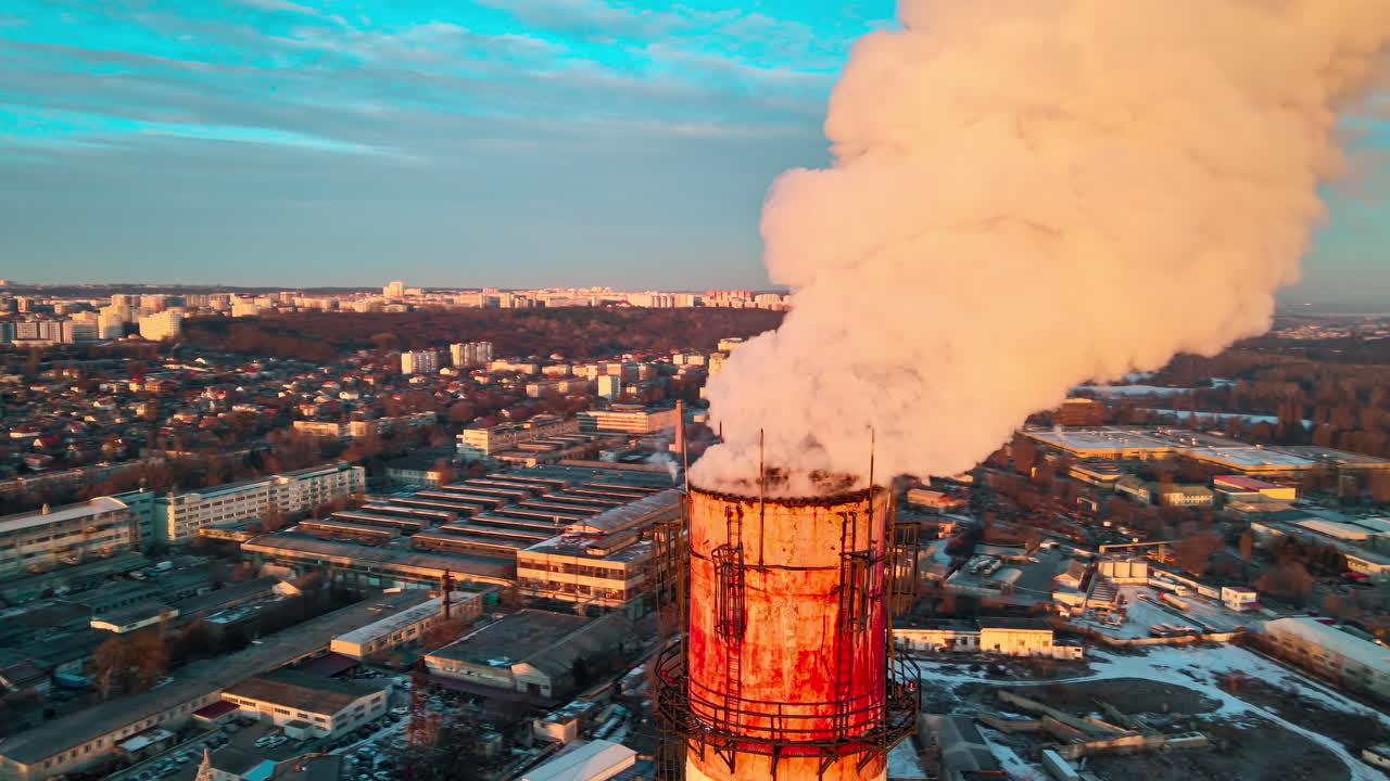 Aerial drone view of Chisinau at sunrise. Thermal station with smoke coming out of the tube. Buildings, roads and bare trees on the background. Good weather, snow on the ground. Moldova