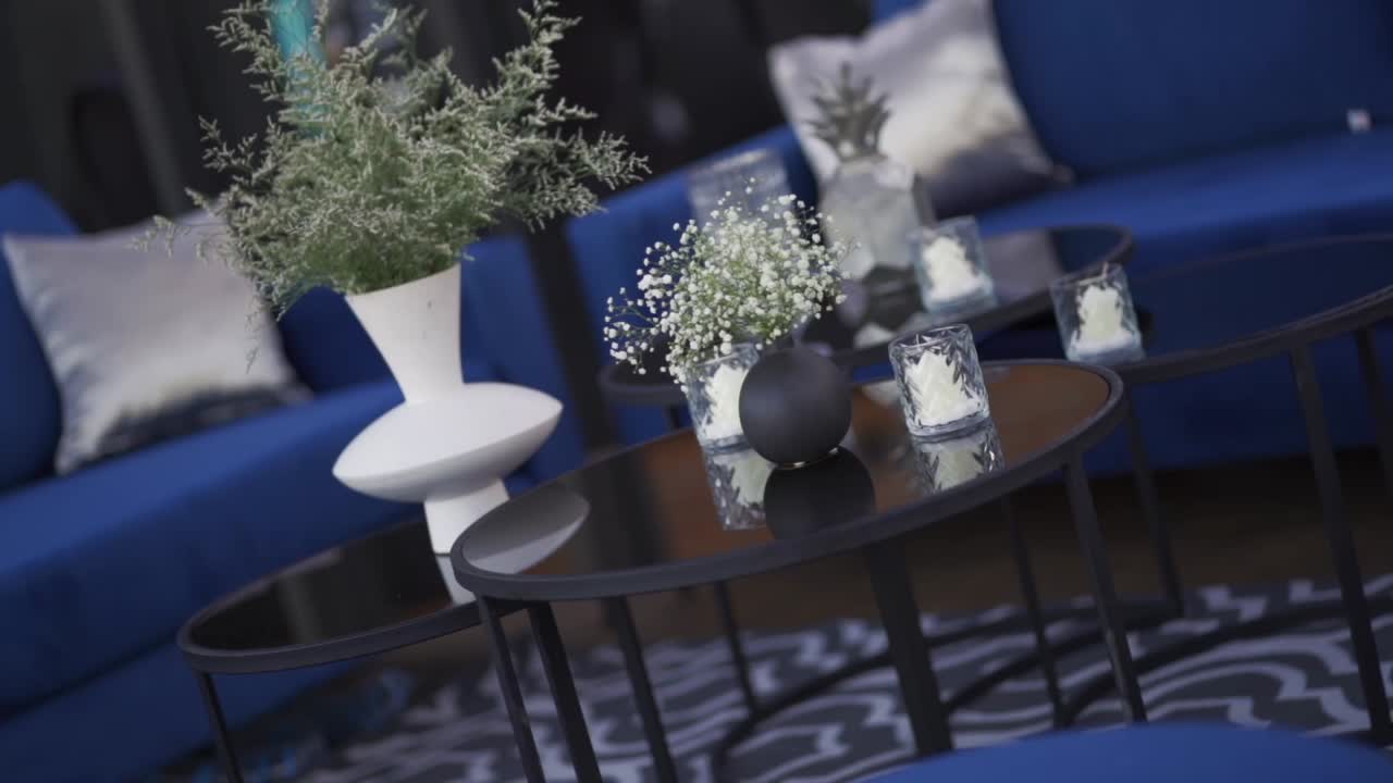 Tavoli rotondi in vetro con decorazioni eleganti, vasi moderni con fiori di gypsophila.