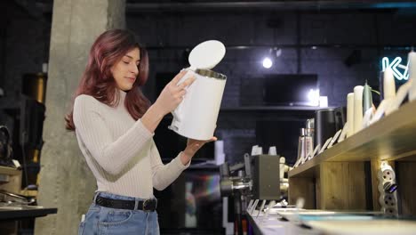 a woman examines an electric kettle in an electronics store