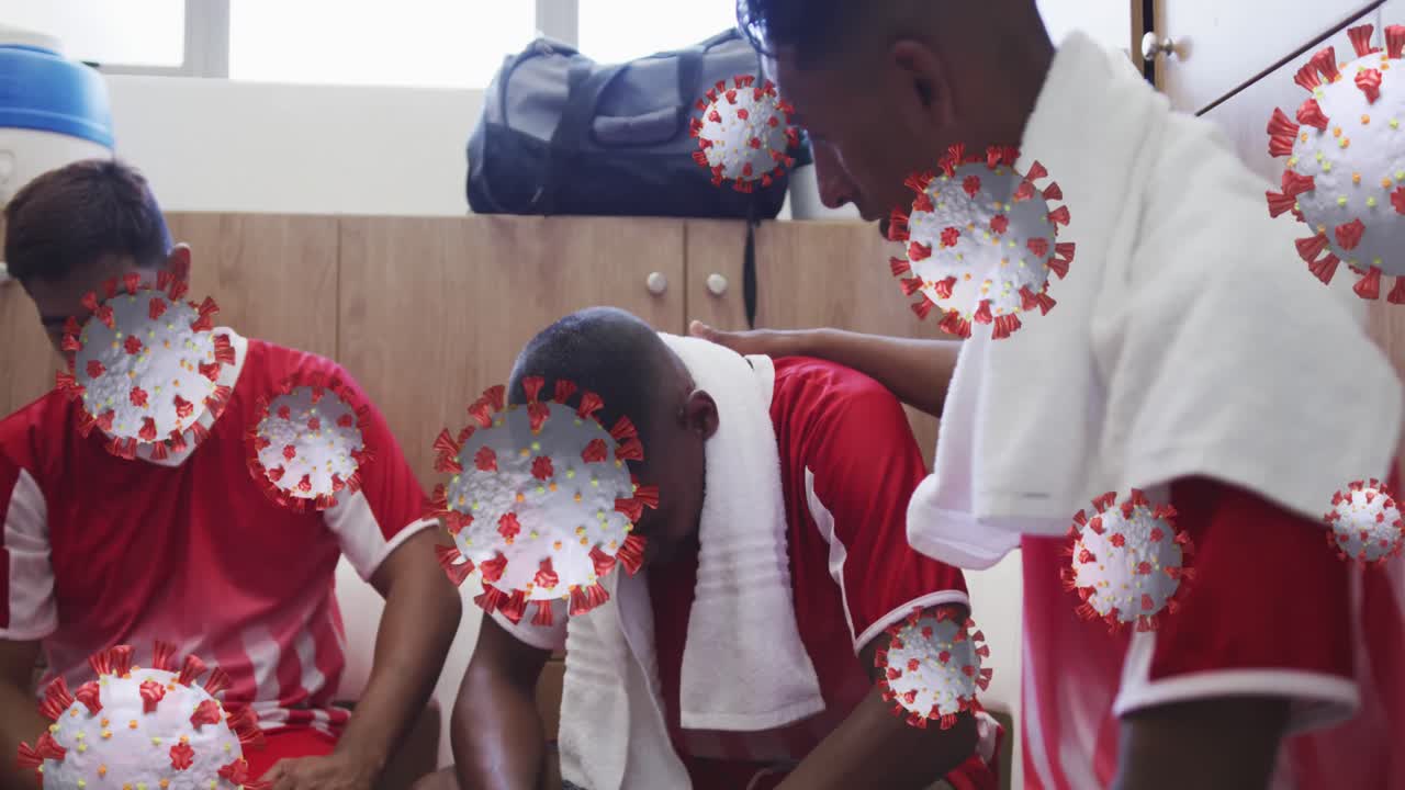 코로나19 세포는 남자 축구 선수가 옷차림실에서 팀 동료를 지원하는 것에 대해 떠다니고 있습니다.