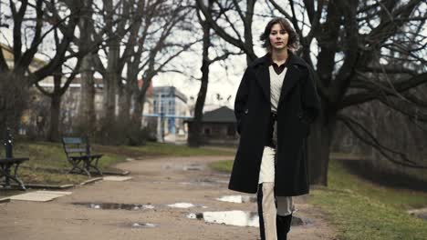 Mujer-Joven-Con-Un-Abrigo-Negro-Caminando-En-Un-Parque-En-Otoño-Por-La-Tarde-5