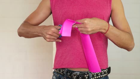 hombre cortando papel de seda rosa con tijeras, centrándose en las manos y la artesanía