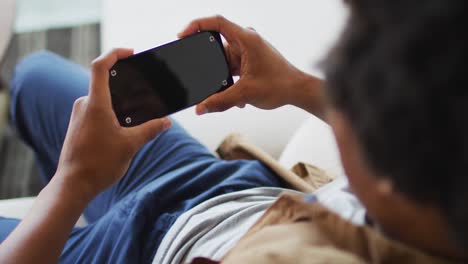hombre afroamericano usando un teléfono inteligente en casa