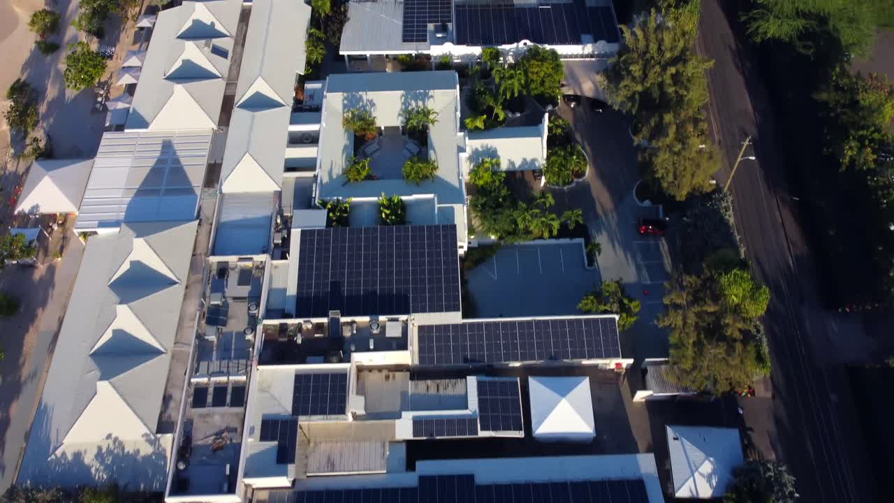 Beachfront property solar panel roofs birdseye tilt to reveal sunny beach strip