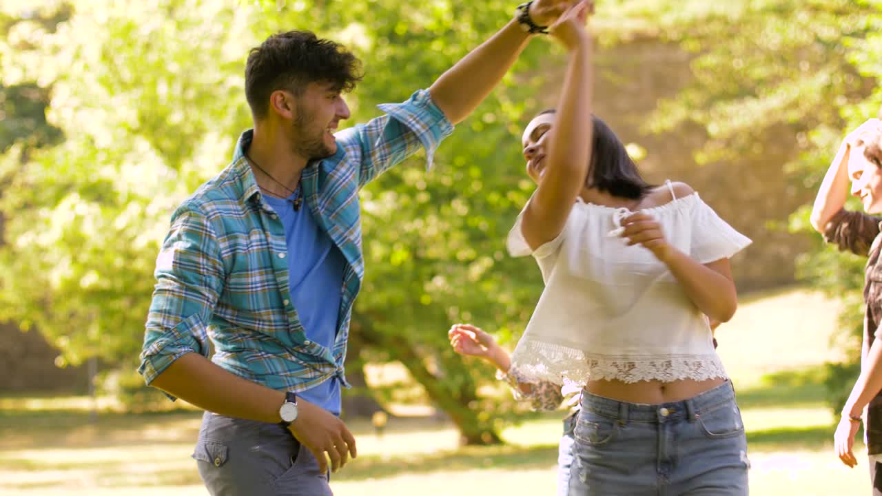 amigos felices bailando en una fiesta de verano en el parque.