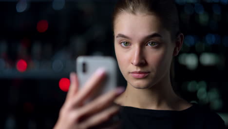 Porträt-Eines-Ernsthaften-Mädchens,-Das-Ein-Selfie-Auf-Dem-Smartphone-Mit-Nachthintergrund-Macht.