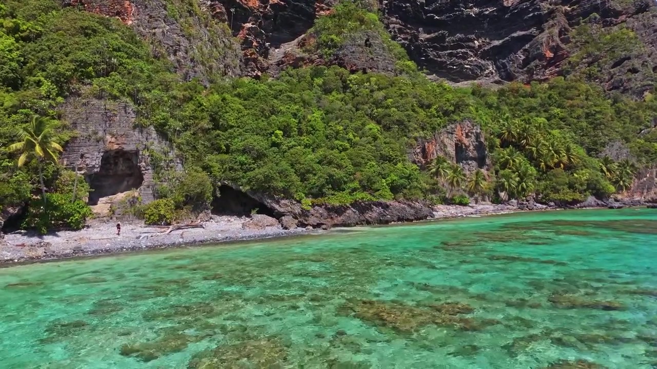 Drone che vola sopra acqua cristallina lungo la costa a picco della penisola di Samaná nella Repubblica Dominicana. Avanzamento aereo.