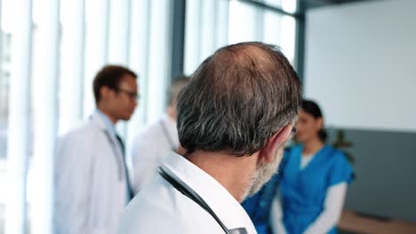 Portrait-Of-The-Senior-Confident-Doctor-Wearing-Medical-Gown-And-Glasses-Looking-At-The-Camera