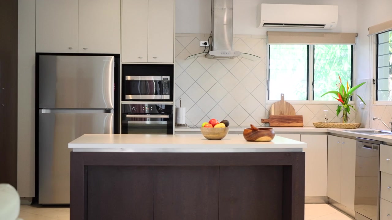 Pan across Luxurious ornately detailed kitchen staged with fruit bowl cutting board and decorative sculptures in loungeroom. Interior of house home for real estate property.