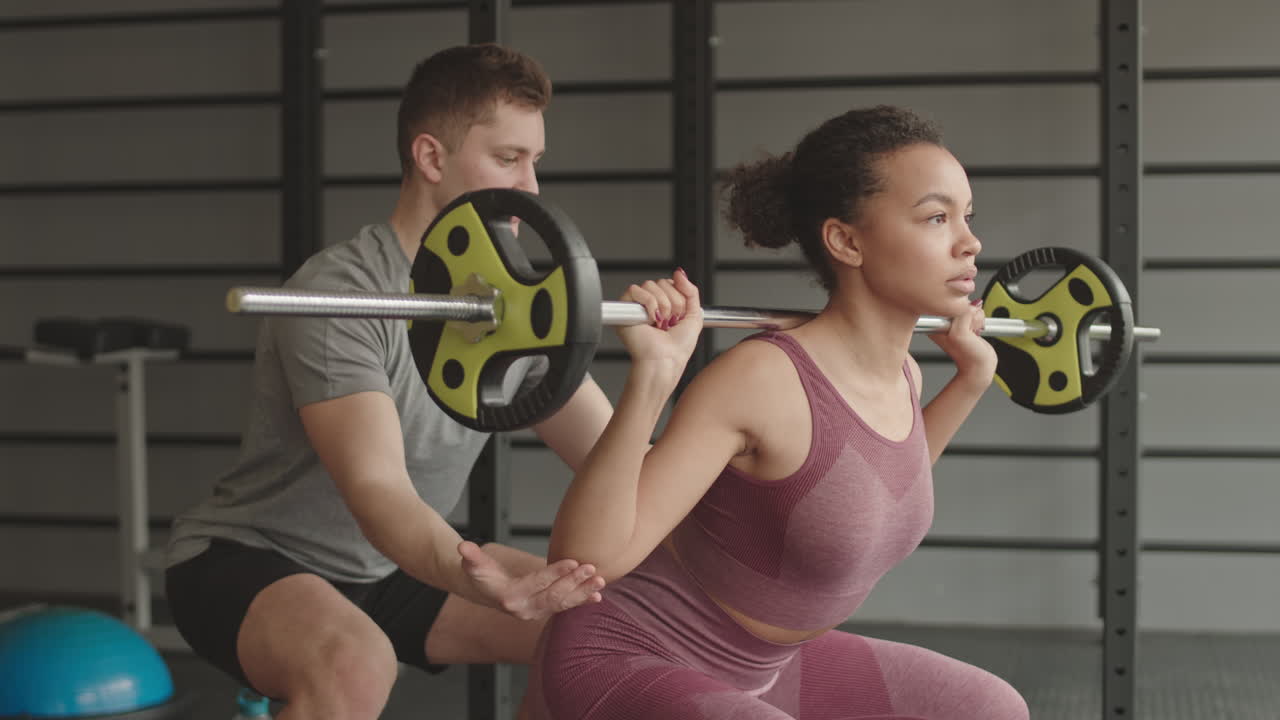 Coach Helping Female Athlete Doing Squats