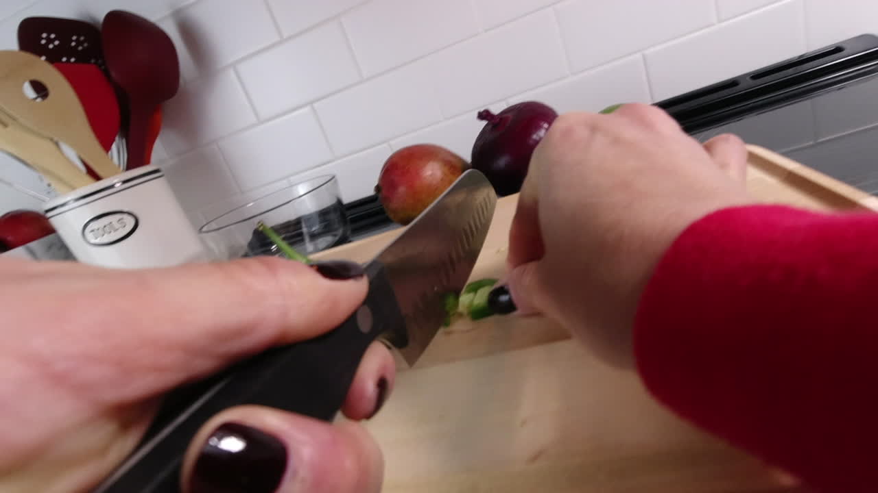 POV shot of woman chopping spicy jalapenos on cutting board