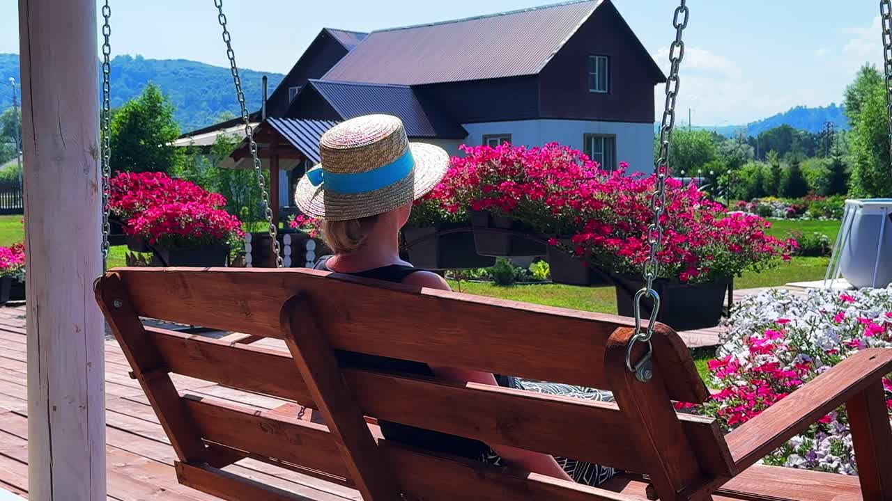 A Serene Afternoon: A Woman Relaxing on a Swing with Vibrant Flowers and Scenic Views in a Peaceful Garden Setting