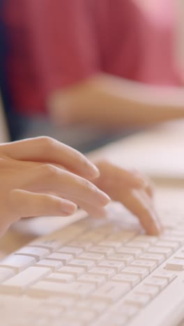 hands of a woman typing computer keyboard in a coworking
