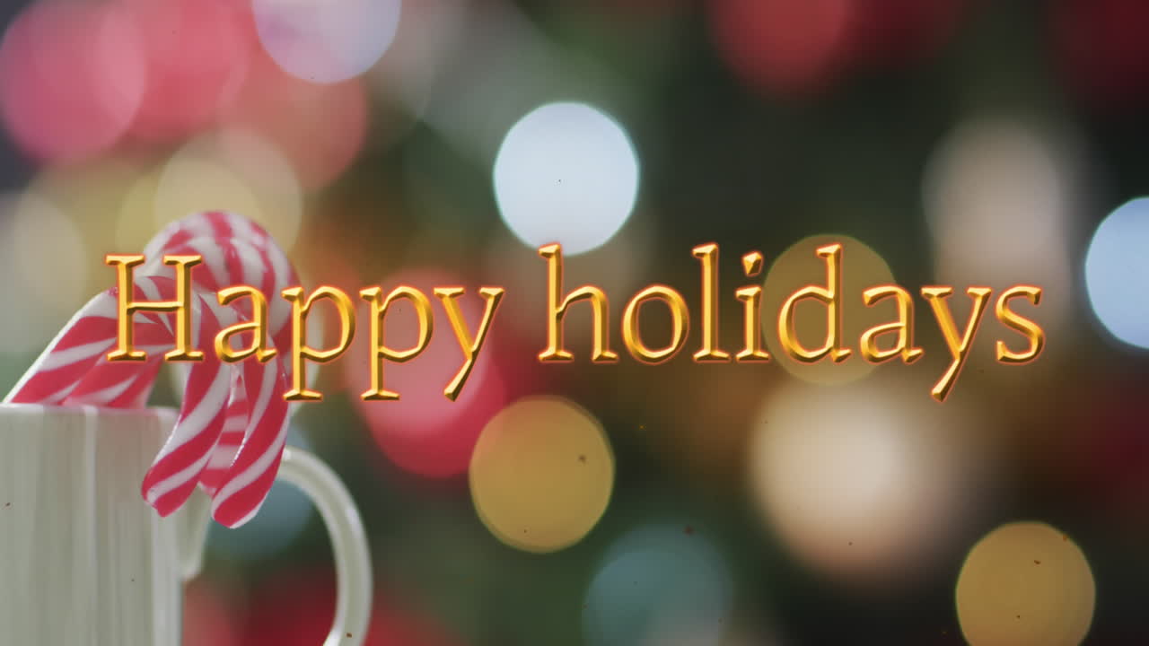 Happy holidays text in orange with candy canes over bokeh christmas lights