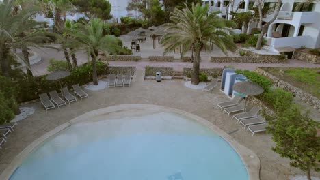 drone dances over mallorca hotel, pool and palm trees views