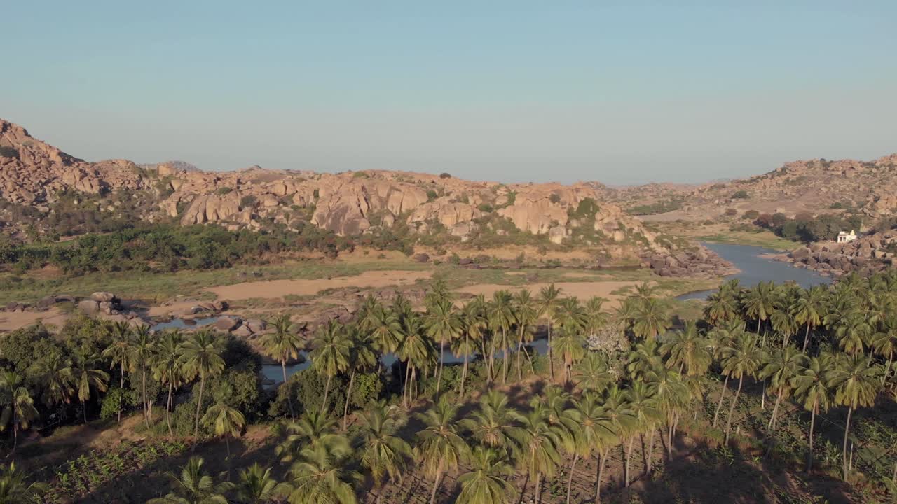 ribera paradisíaca de tungabhadra entre paisajes rocosos y exuberantes palmeras en hampi, karnataka, india - plano panorámico aéreo