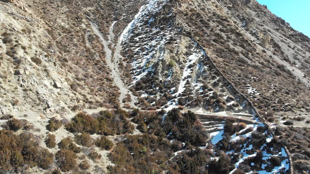 Aerial shot of a Solo trekker walking uphill in Annapurna Circuit Trek, Manang, Nepal.