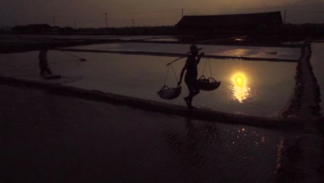 slow motion of salt feild worker workers silhouette against the evening sun in se asia