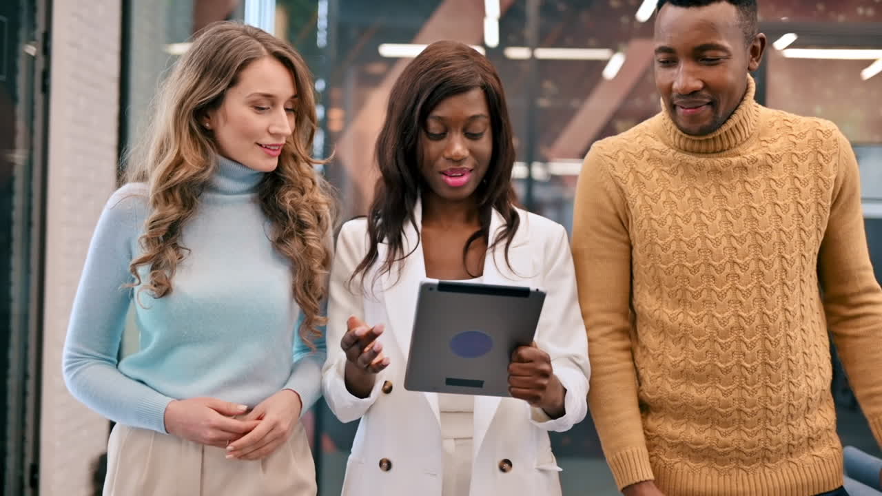Multiracial group of workers walking in an office and discussing business affairs using a tablet. Slow motion