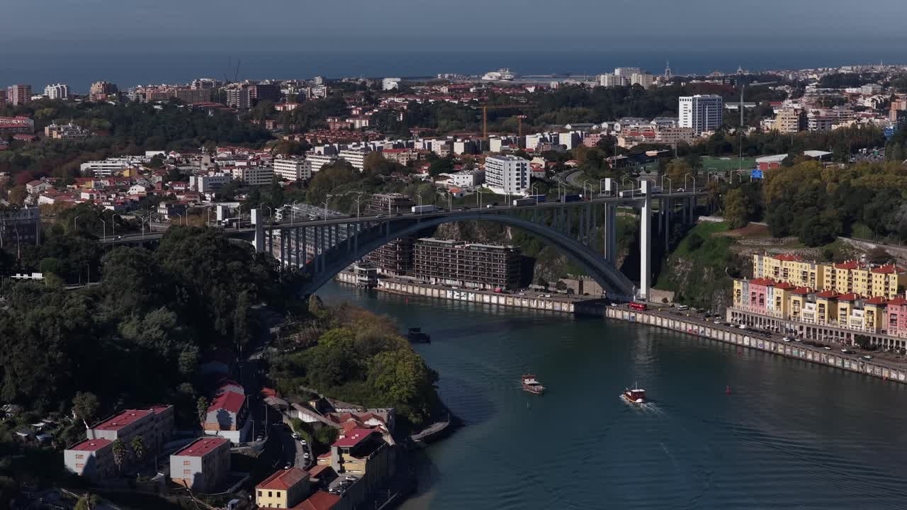 Cityscape of Porto Arrabida bridge and boats on the Douro river on a sunny day