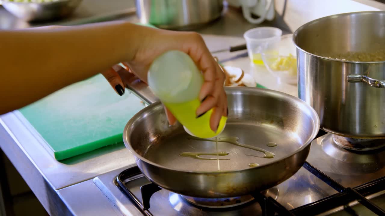 Chef colocando óleo na frigideira na cozinha 4k