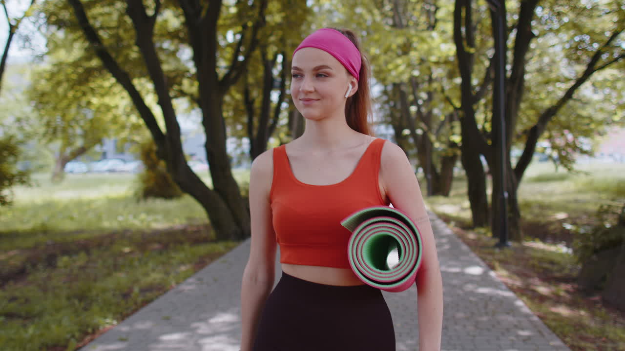 fitness atlético corredora deportiva chica caminando con estera de yoga deportiva para hacer ejercicios de estiramiento de fitness