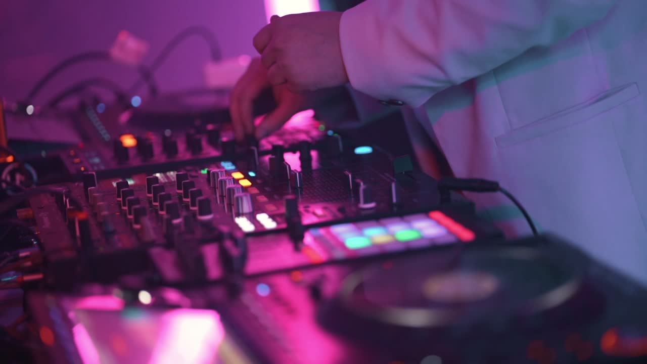 DJ che opera una console di missaggio con manopole, fader e pad illuminati sotto illuminazione al neon, con profondità di campo ridotta e riflessi dinamici, leggero movimento di rollio della telecamera, primo piano al rallentatore.