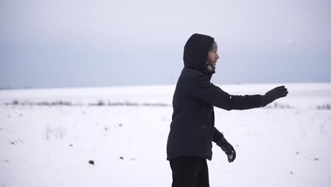 playful young woman outdoor enjoying first snow, throwing a snowball to friend's back