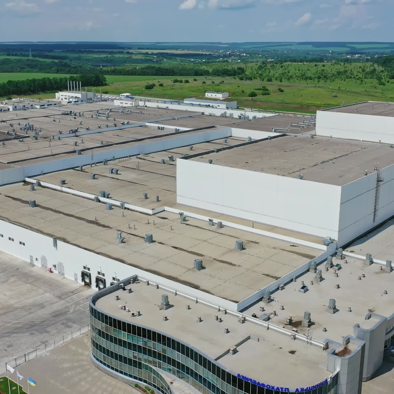 Manufacturing complex outdoors. Exterior of modern factory in the countryside. Large industrial area among green fields. Aerial view.
