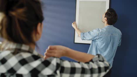 Video-Einer-Frau-Schlägt-Einem-Mann-Vor,-Wie-Man-Ein-Bild-Aufhängt.