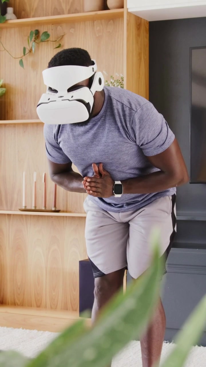 Vertical video: Starting VR, man wearing headset, athletic clothes bowing at home for meditation