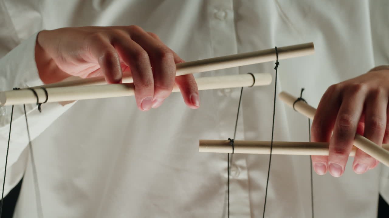 Close-up of Hands Operating Puppet Control Sticks
