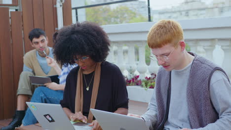 young colleagues working with laptops and speaking outdoors