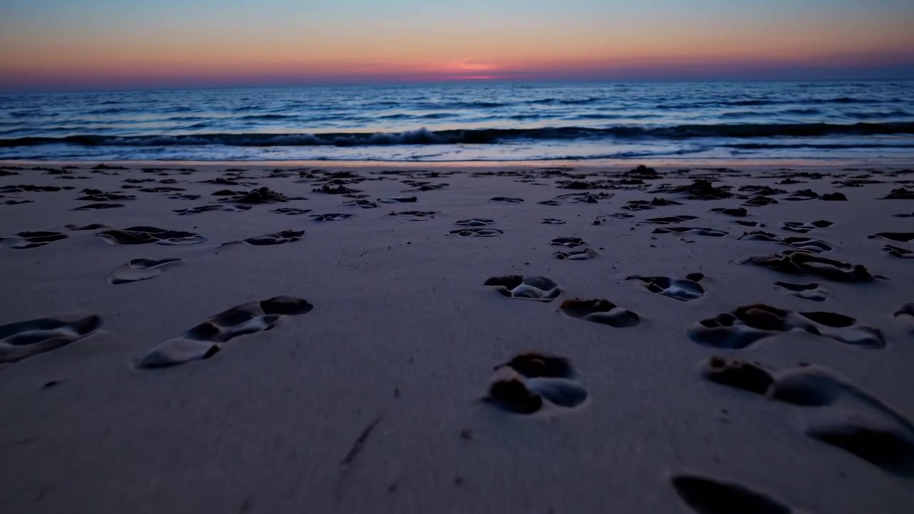 Vista dal basso di impronte sulla sabbia della spiaggia al tramonto