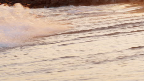 Sunset-scene-of-foamy-sea-waves-rolling-in-on-the-shore