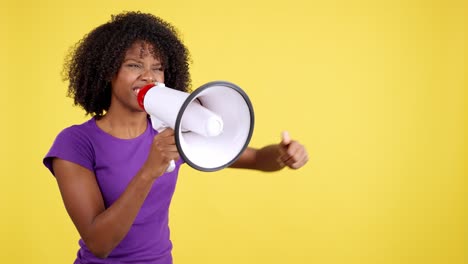 powerful woman with megaphone shouting and raising fist on yellow background