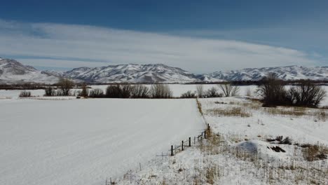 drone flying over serene frozen lake in the winter at pineview reservoir in northern utah , to reveal beautiful breathtaking mountains in the background