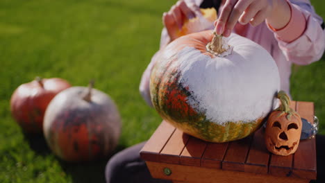 child paints pumpkins, prepares jewelry for helloween