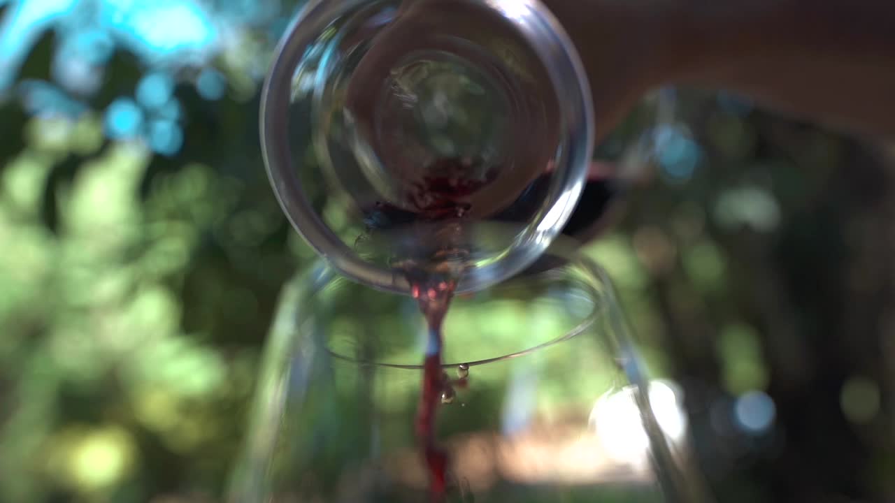 Hælder vin fra en dekanter i et smukt vinglas med grøn bund, hvilket fremhæver kunsten inden for vinservering og præsentation