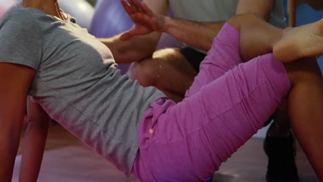 Physiotherapist-assisting-woman-while-exercising-on-exercise-mat