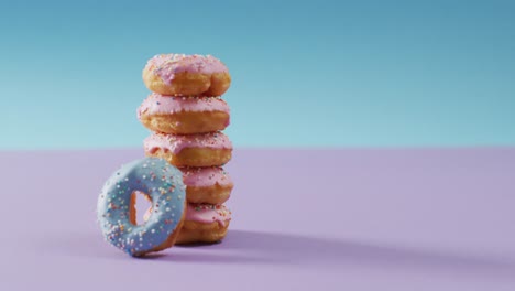 video of donuts with icing on pink and blue background